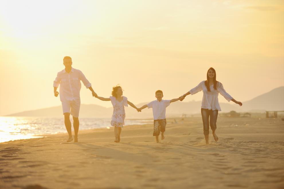 Family of four running along the beach