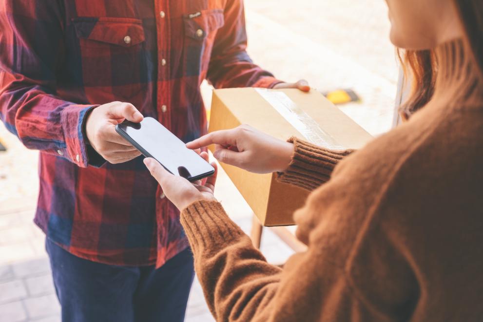 Image of a woman receiving parcel box and using the delivery man's phone to sign