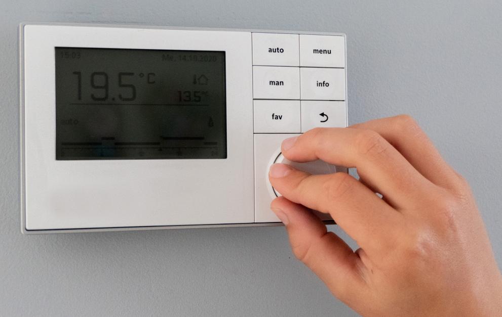 A person adjusting the temperature on a thermostat