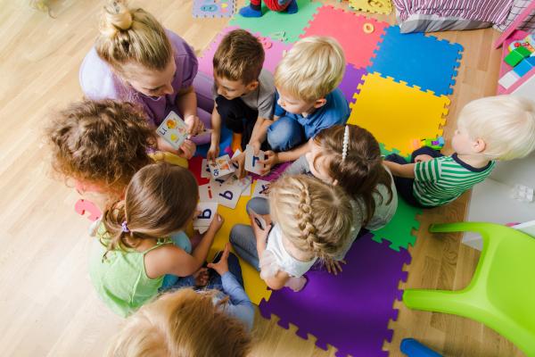 Kindergarteners sitting in a circle on a carpet looking at alphabet cards