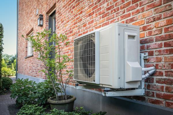 Image of a heat pump on the external wall of a brick house