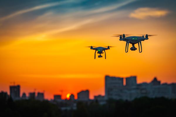 Drones flying in the sunset with buildings in background