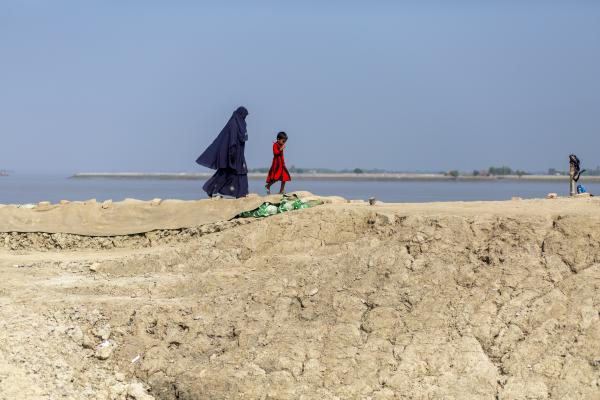 A woman and child walk along the embankment in Labubunia village in Satkhira, Bangladesh
